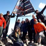 Group of trekkers celebrating on the summit of Mount Toubkal in Morocco