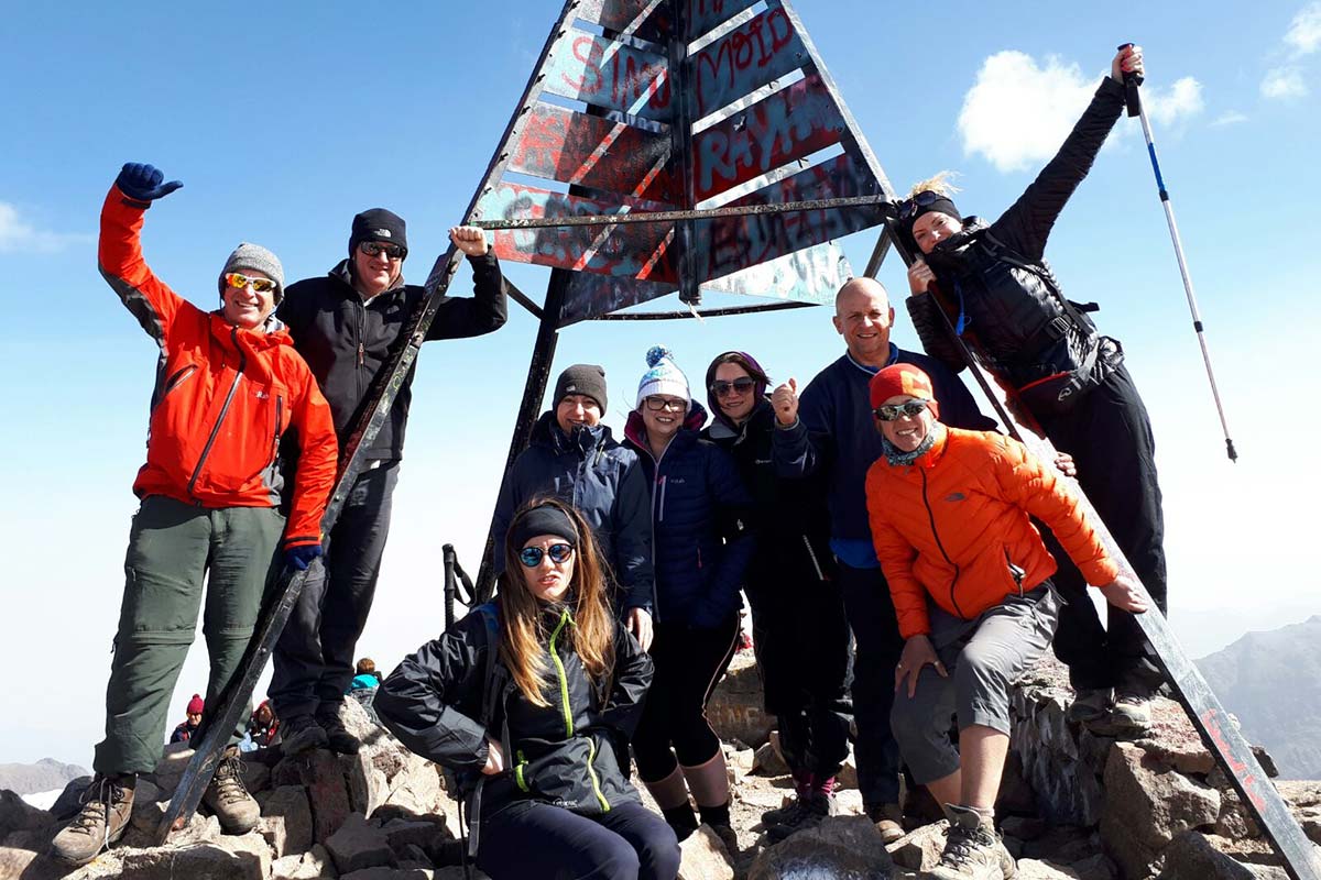 Group of trekkers celebrating on the summit of Mount Toubkal in Morocco