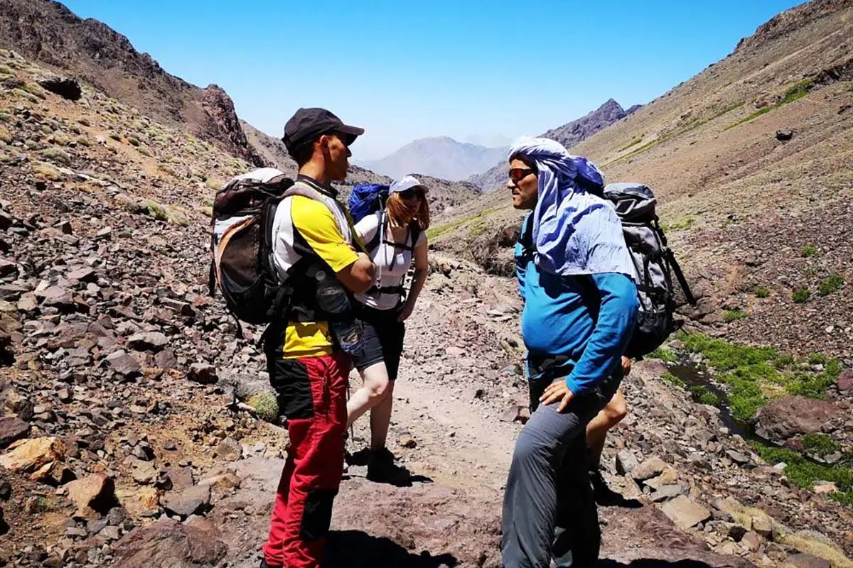 Local mountain guide speaking with hikers on a trail in Toubkal National Park