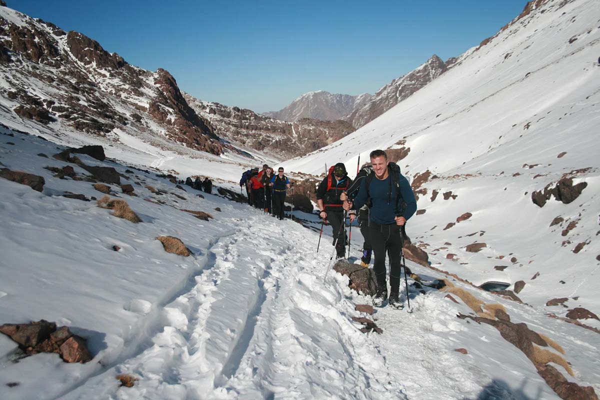 Trekkers hiking through snow on the winter trail to Mount Toubkal in the High Atlas Mountains