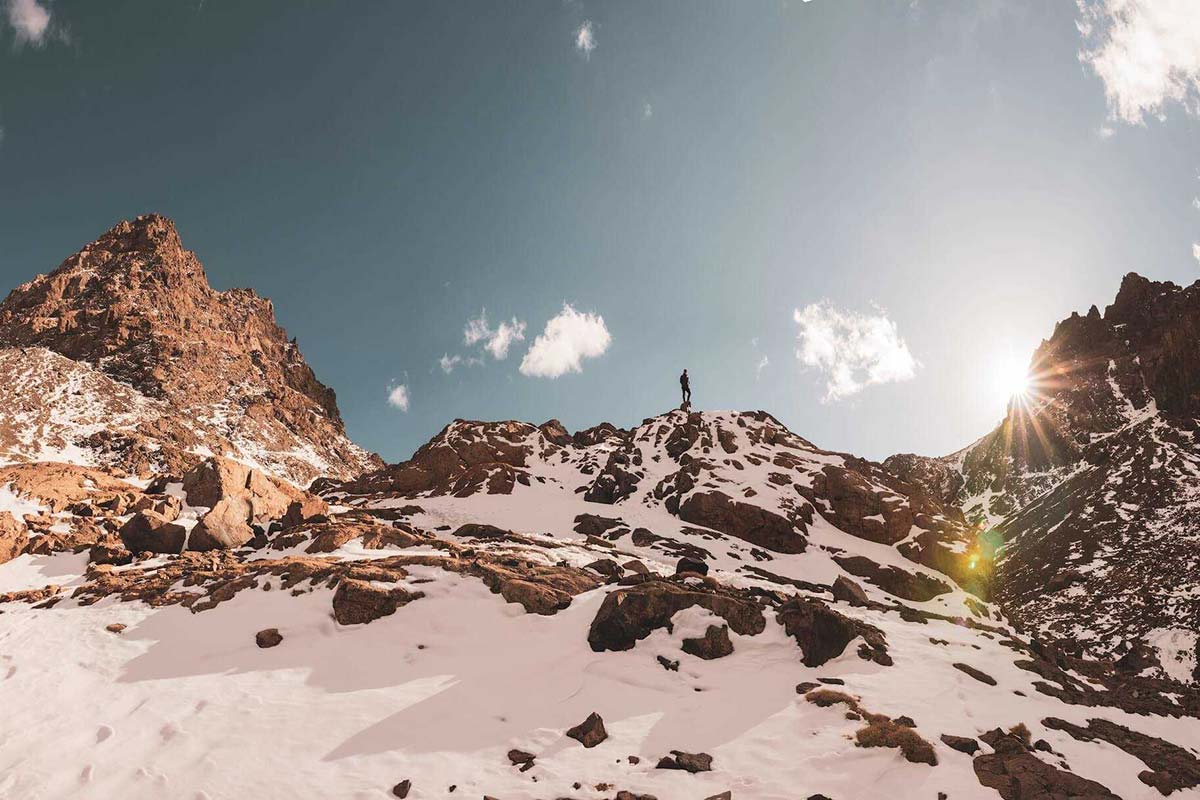 Hiker standing on snowy rocks in the High Atlas Mountains with winter sunlight
